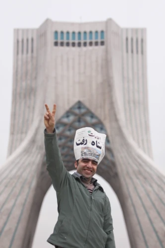 Iranian man shows the victory sign in front of Azadi tower